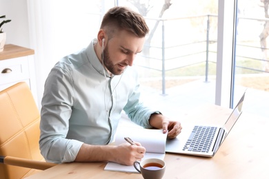 Young man working with laptop at desk. Home office