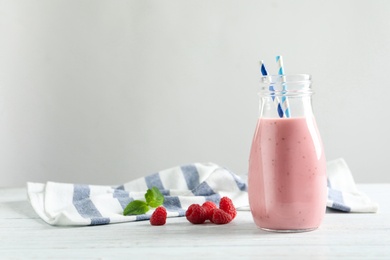 Image of Yummy raspberry smoothie in glass bottle on table. Space for text 