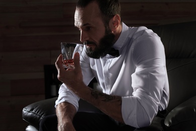 Photo of Man with glass of whiskey sitting in armchair indoors