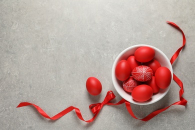 Bowl with red painted Easter eggs on table, top view. Space for text