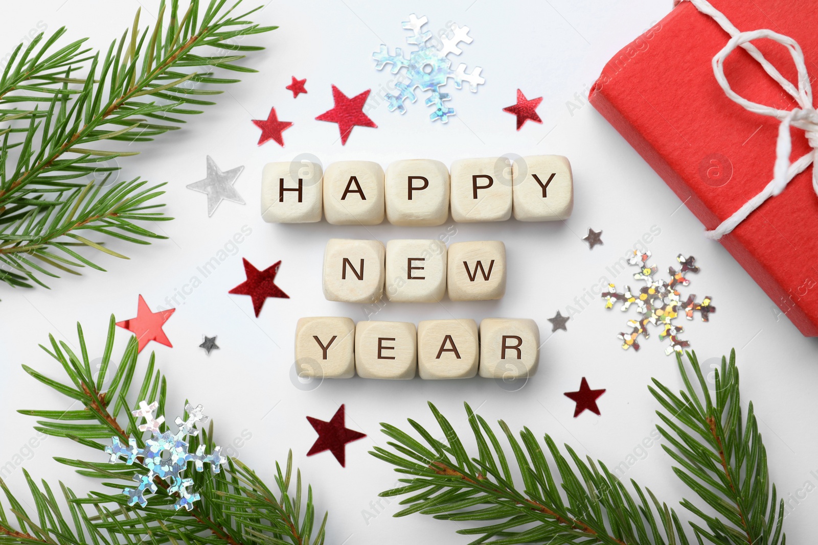 Photo of Happy New Year greeting card. Phrase made with cubes and festive decor on white background, flat lay