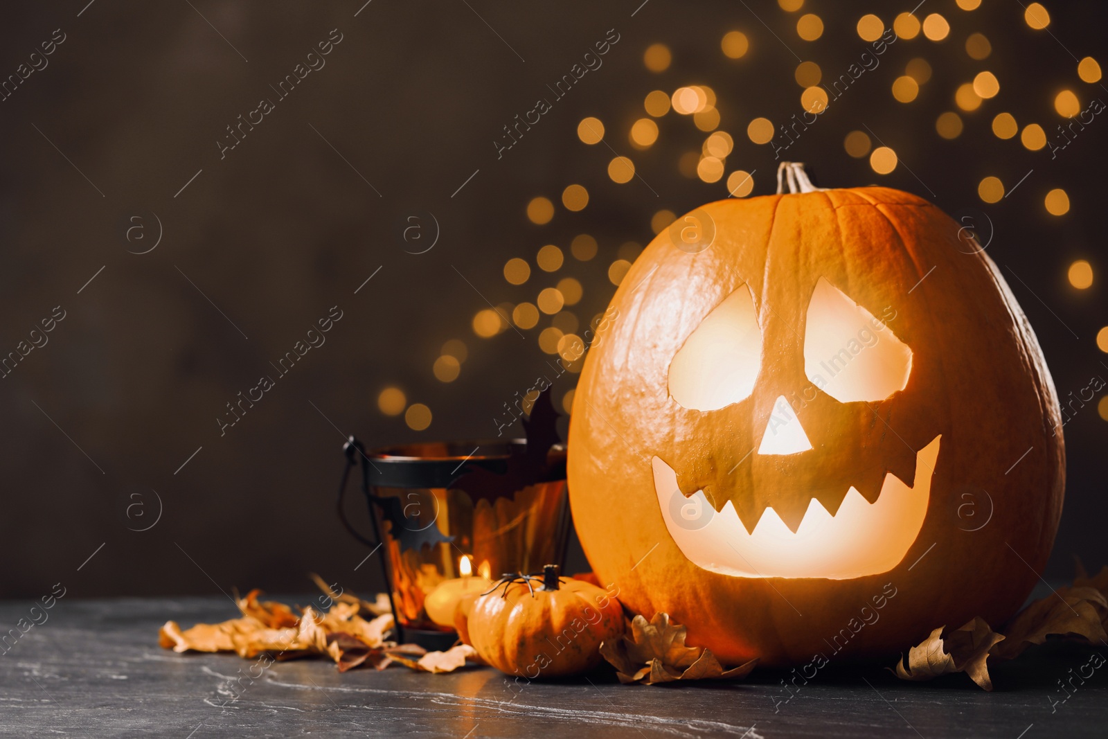 Photo of Pumpkin jack o'lantern and Halloween decor on table against blurred background, space for text