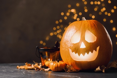 Photo of Pumpkin jack o'lantern and Halloween decor on table against blurred background, space for text