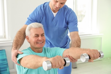 Professional physiotherapist working with senior patient in rehabilitation center