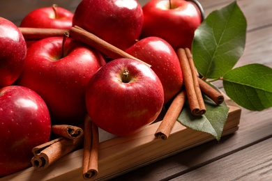 Photo of Fresh apples and cinnamon sticks on wooden table