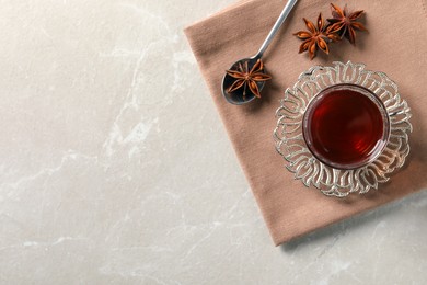 Glass of traditional Turkish tea in vintage holder and anise stars on white marble table, top view. Space for text