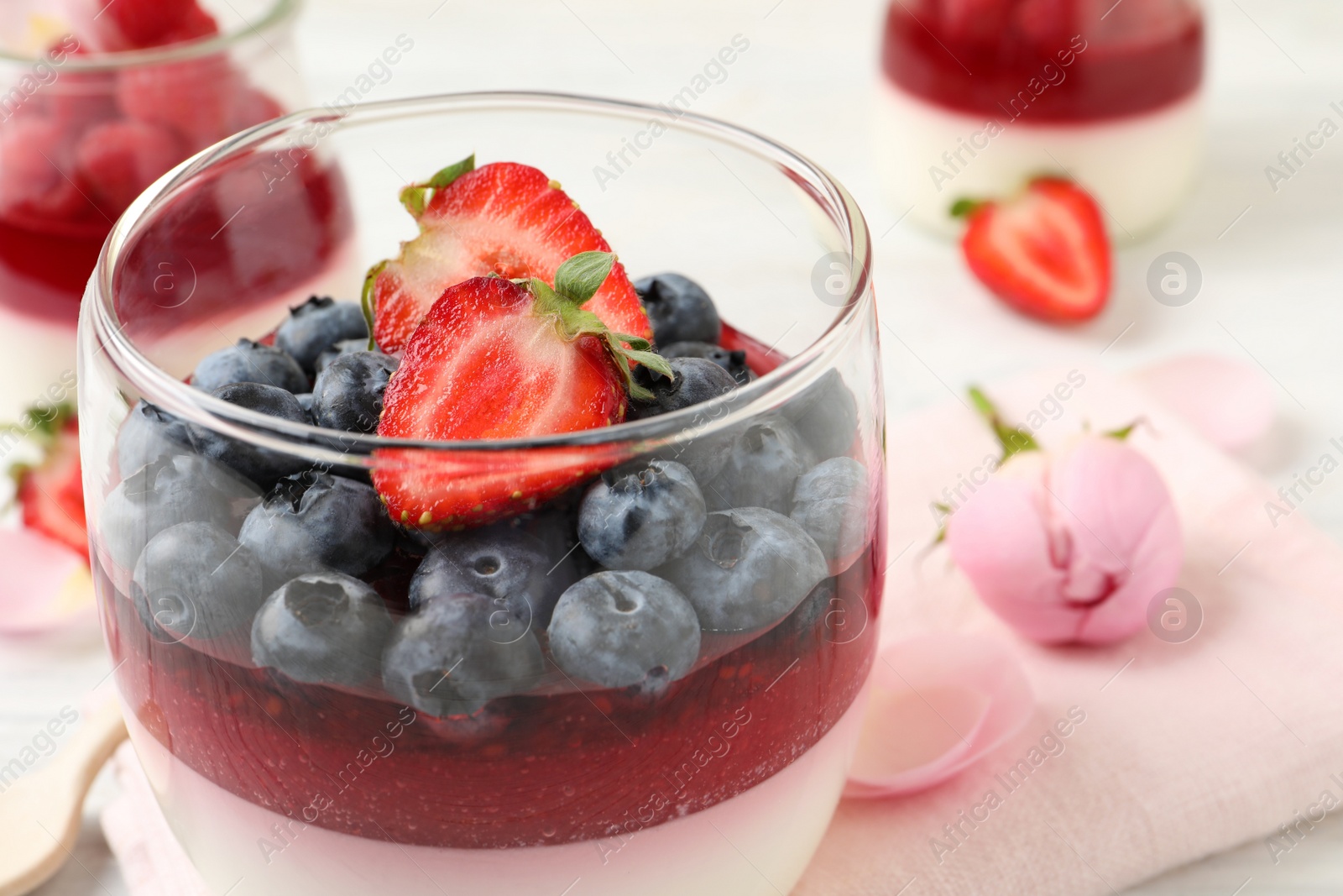 Photo of Delicious panna cotta with berries in glass dish, closeup