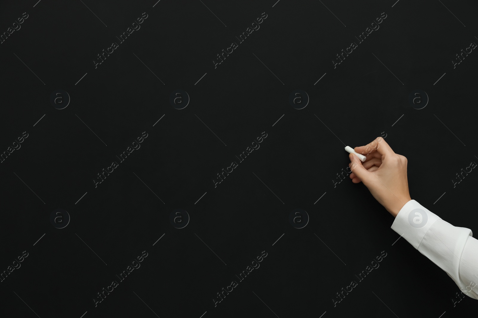 Photo of Woman with white chalk near blackboard, closeup. Space for text