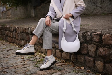 Stylish woman with trendy white baguette bag on city street, closeup