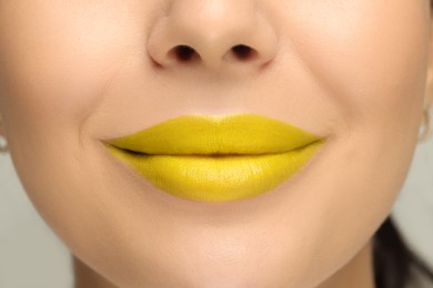 Woman with yellow lipstick on light background, closeup