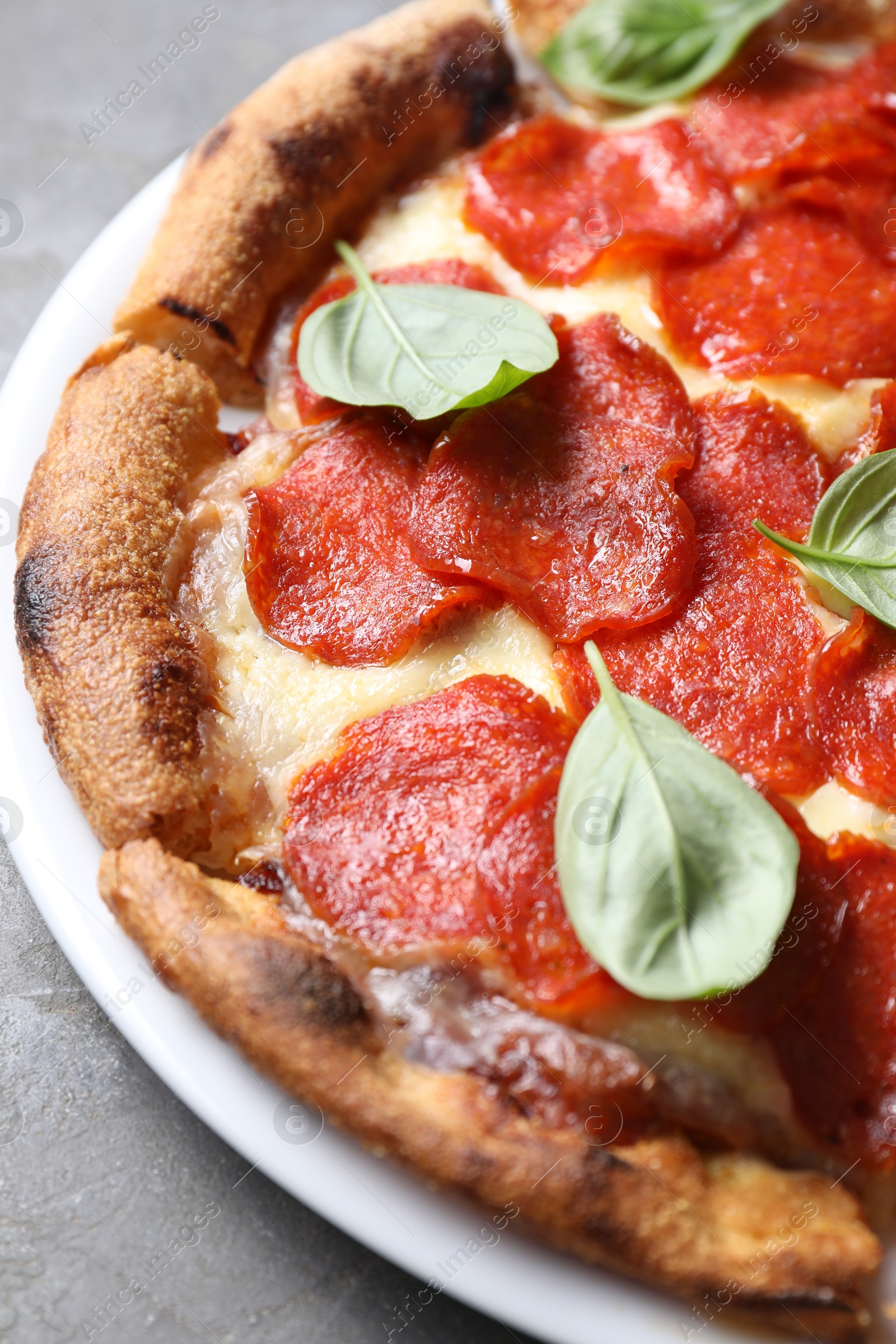 Photo of Tasty pepperoni pizza with basil on grey table, closeup