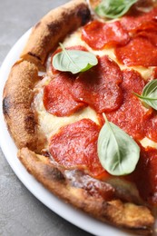 Tasty pepperoni pizza with basil on grey table, closeup