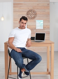 Photo of Handsome young man sitting near table at home