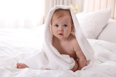 Photo of Cute little baby with soft towel on bed after bath