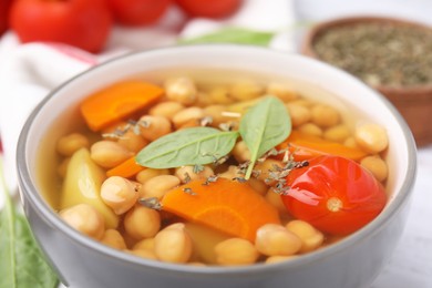 Photo of Tasty chickpea soup in bowl and spices on table, closeup