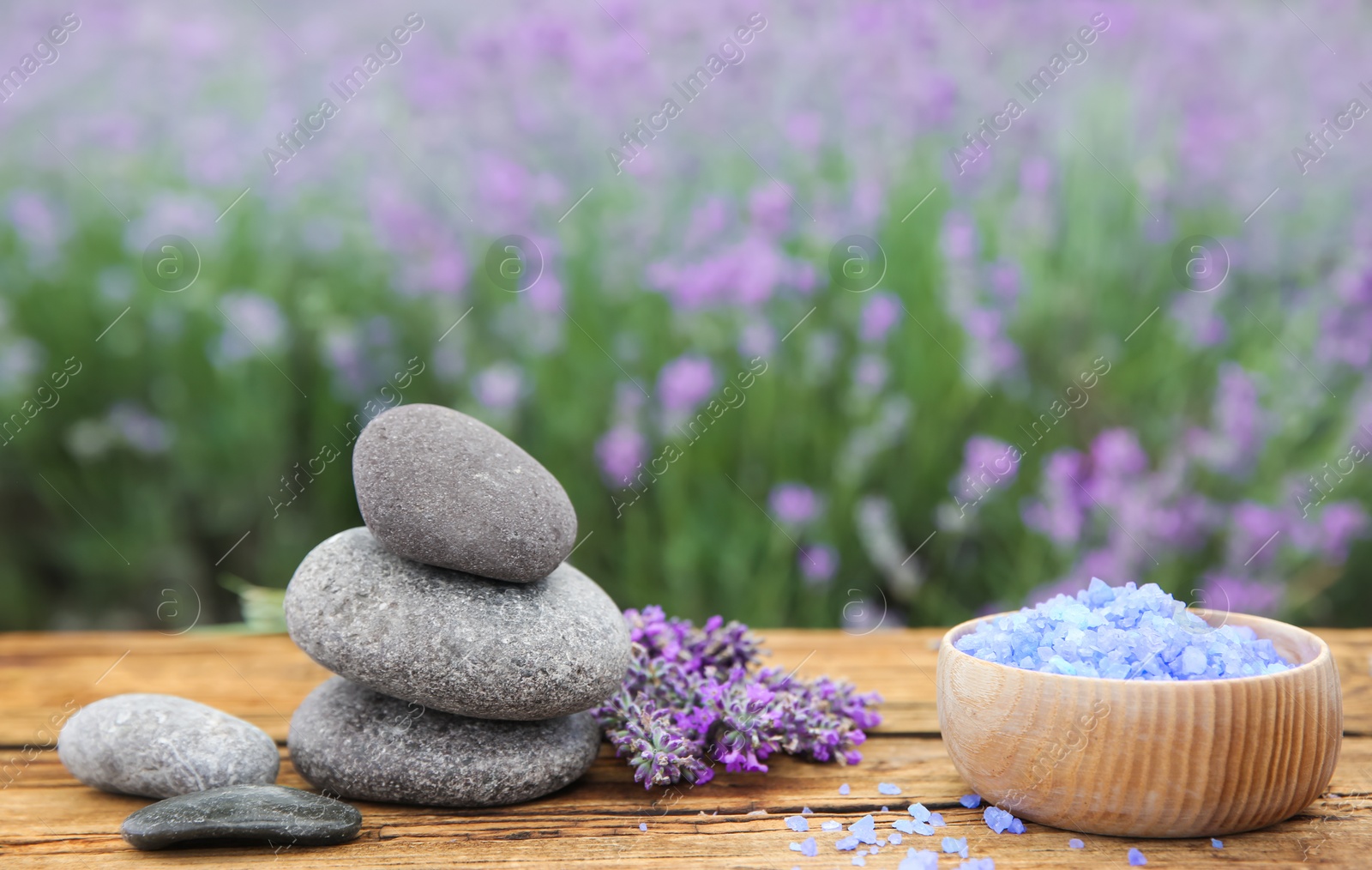 Photo of Spa stones, fresh lavender flowers and bath salt on wooden table outdoors, closeup