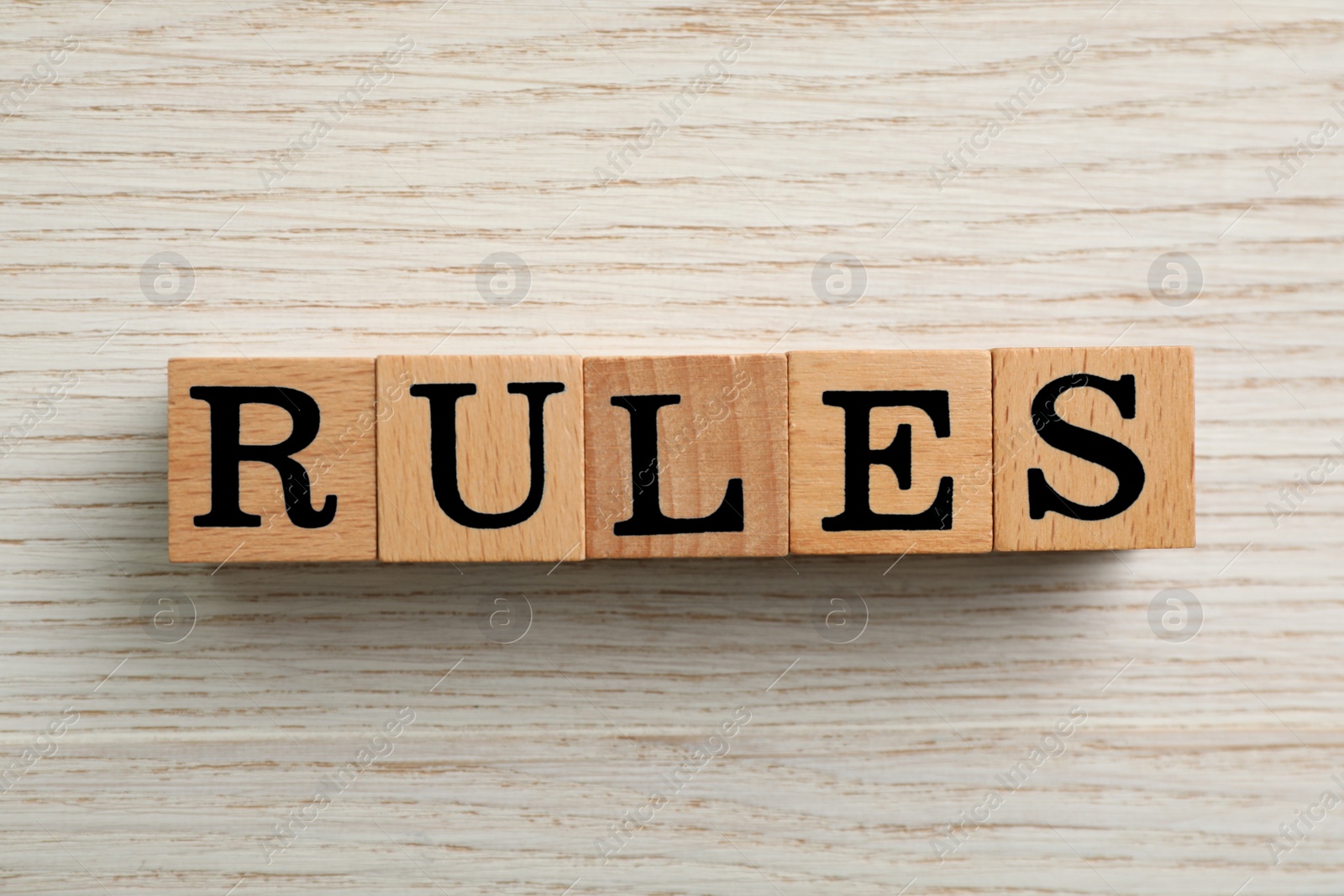 Photo of Word Rules made of cubes with letters on light wooden table, top view