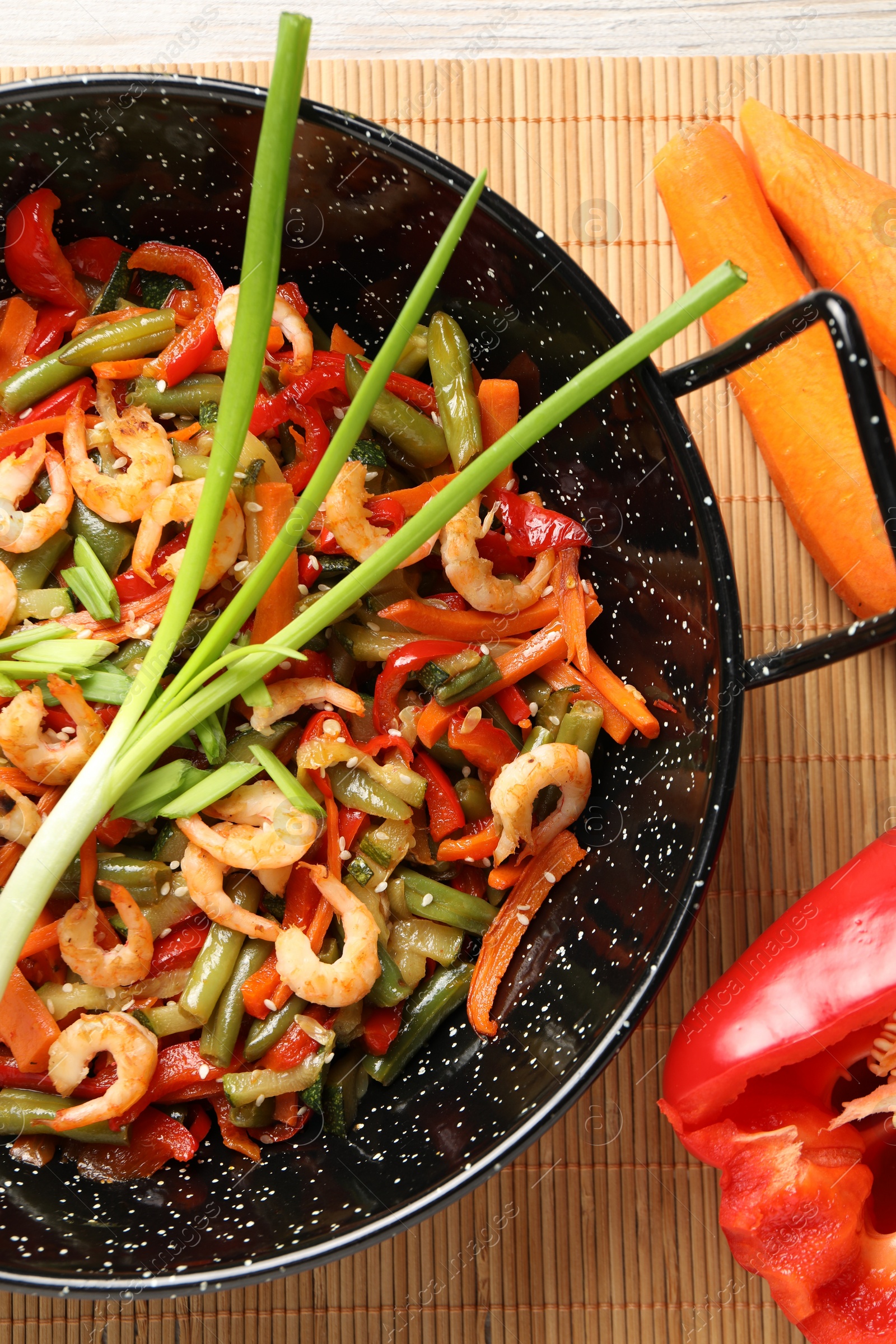 Photo of Shrimp stir fry with vegetables in wok and ingredients on table, flat lay