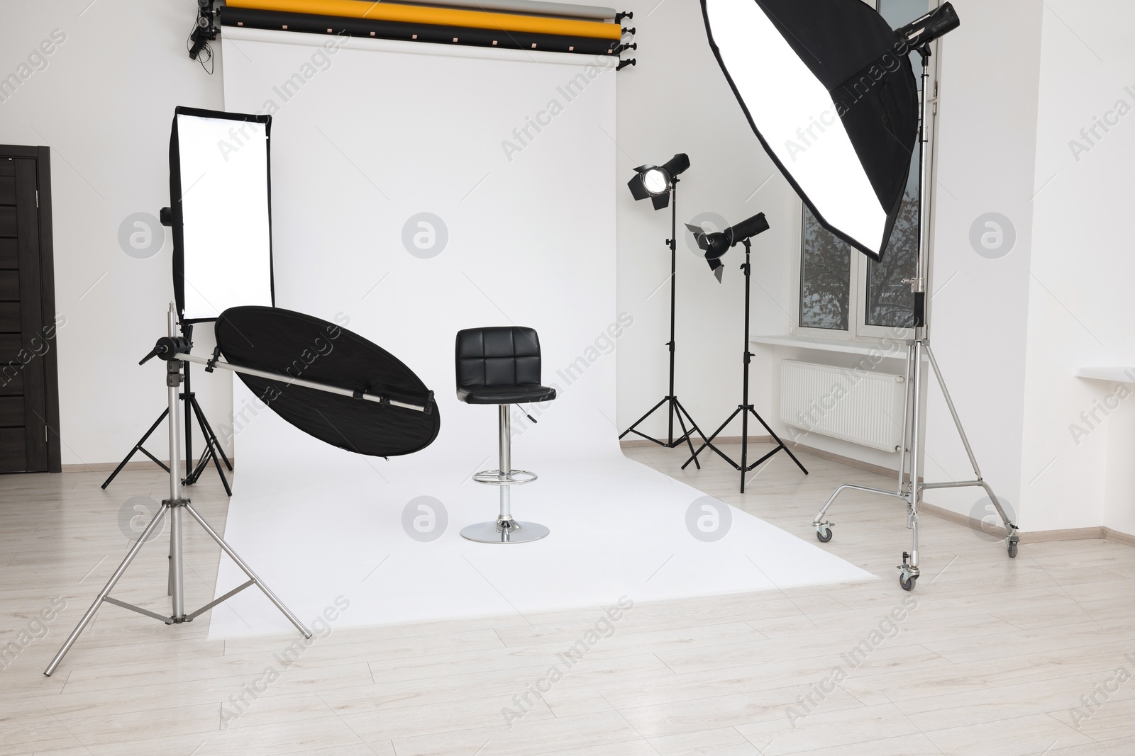 Photo of Interior of modern photo studio with bar stool and professional lighting equipment