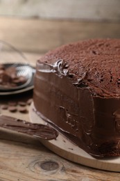 Delicious homemade layer cake with chocolate cream on wooden table, closeup