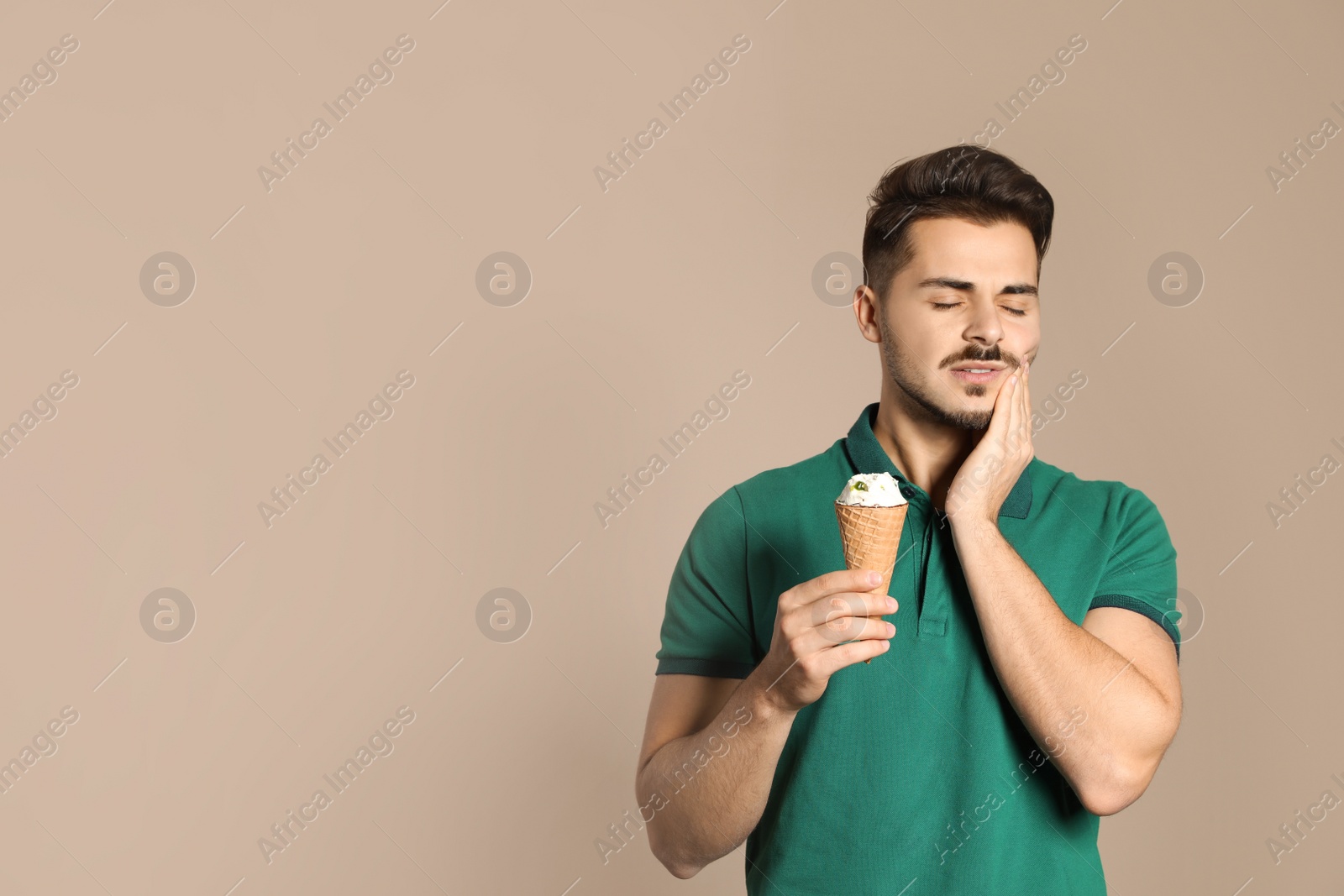 Photo of Emotional young man with sensitive teeth and ice cream on color background. Space for text