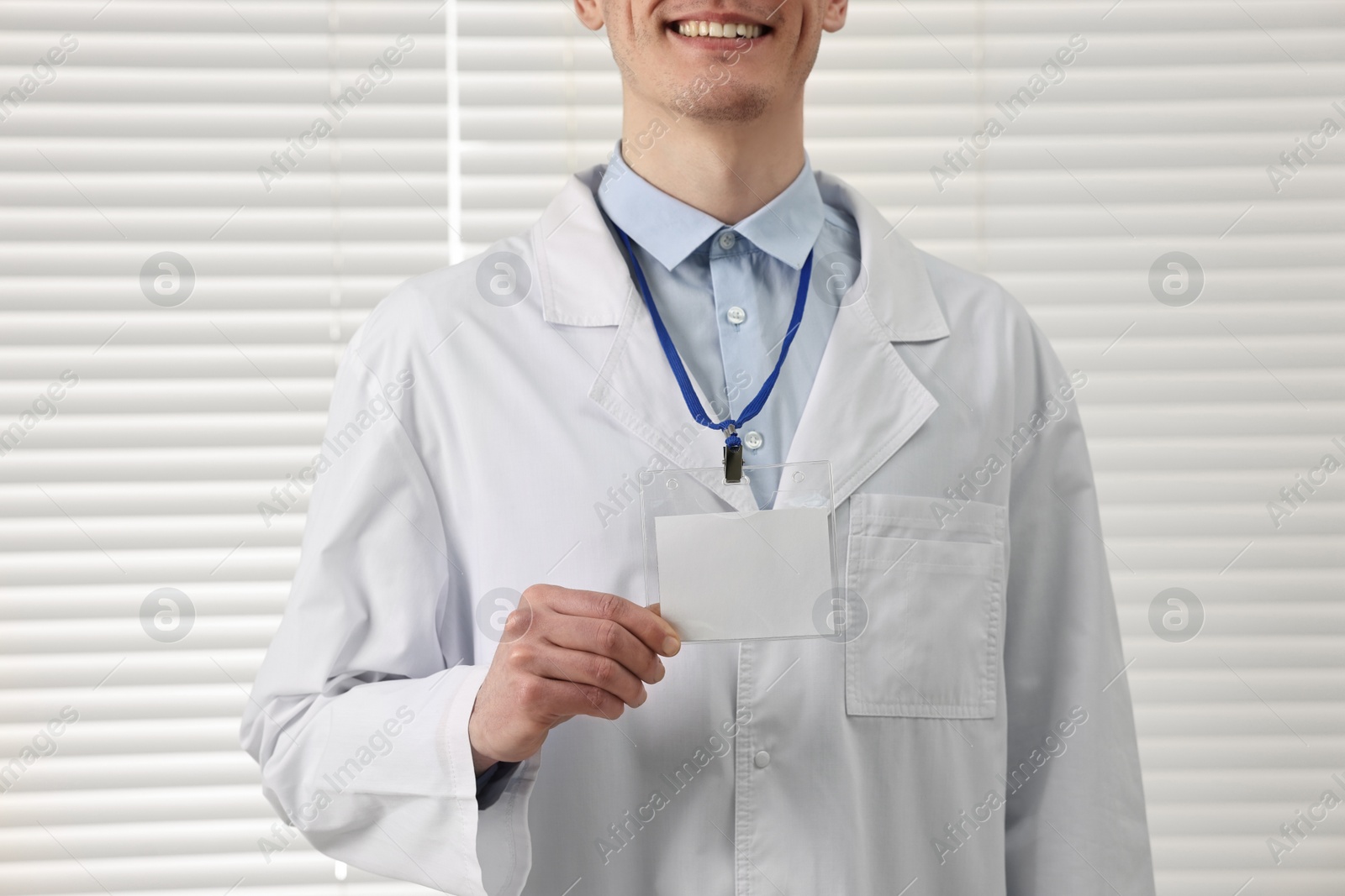 Photo of Smiling doctor showing empty badge in hospital, closeup