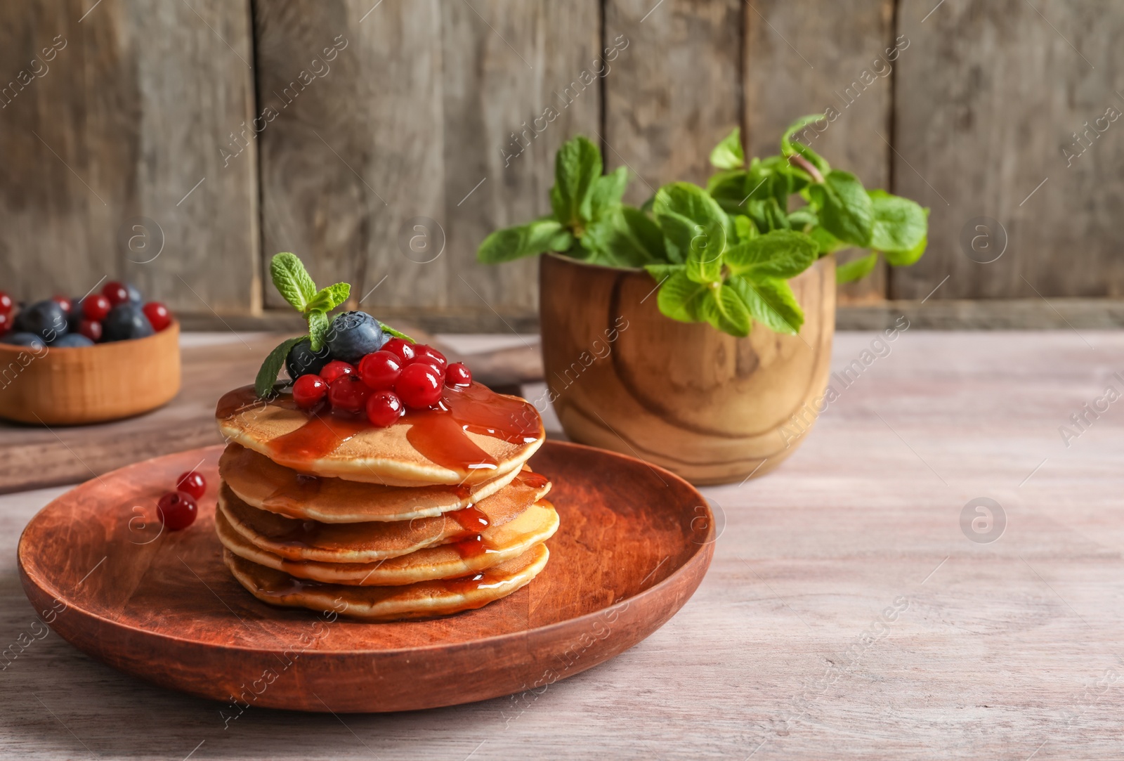 Photo of Stack of tasty pancakes with berries and syrup on table