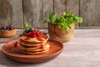 Photo of Stack of tasty pancakes with berries and syrup on table