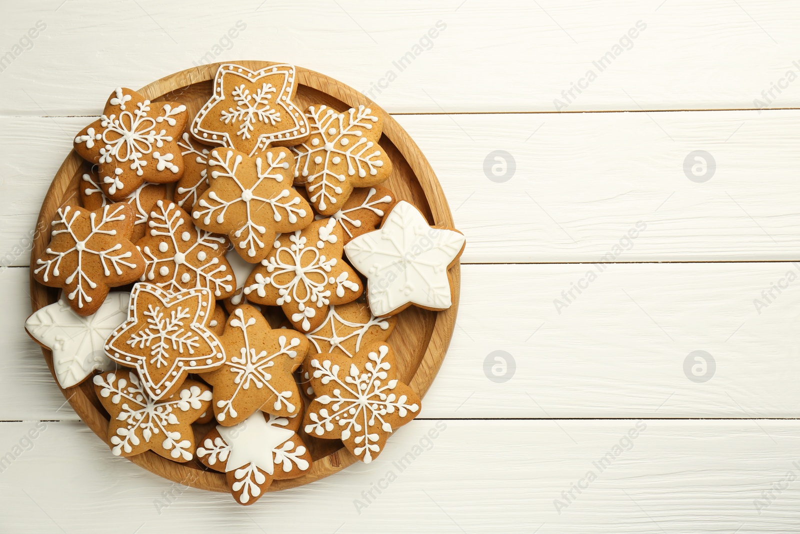 Photo of Tasty Christmas cookies with icing on white wooden table, top view. Space for text