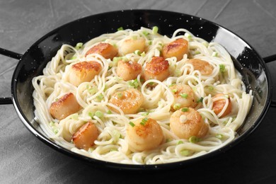 Photo of Delicious scallop pasta with green onion on grey table