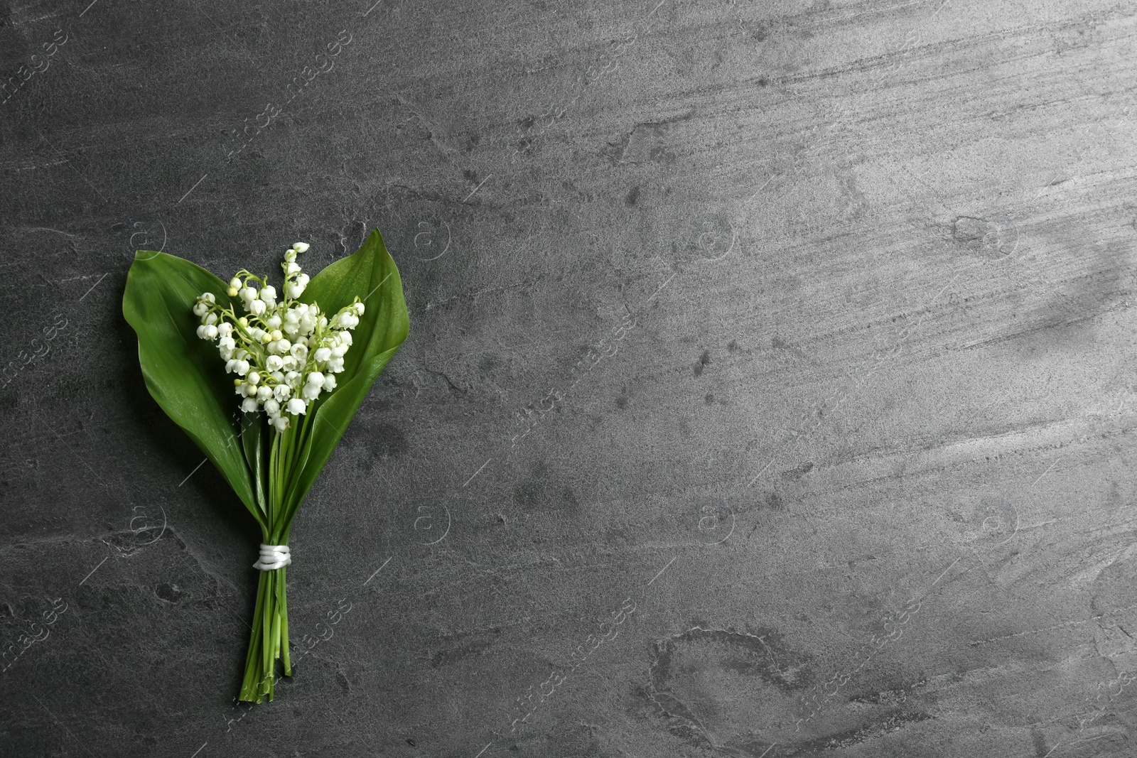 Photo of Beautiful lily of the valley bouquet on grey background, top view. Space for text