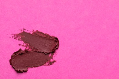 Photo of Smears of beautiful lipstick on pink background, top view. Space for text