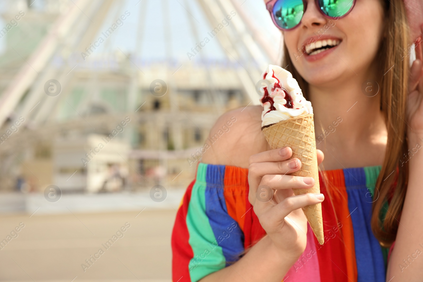 Photo of Young happy woman with ice cream cone in amusement park, closeup. Space for text