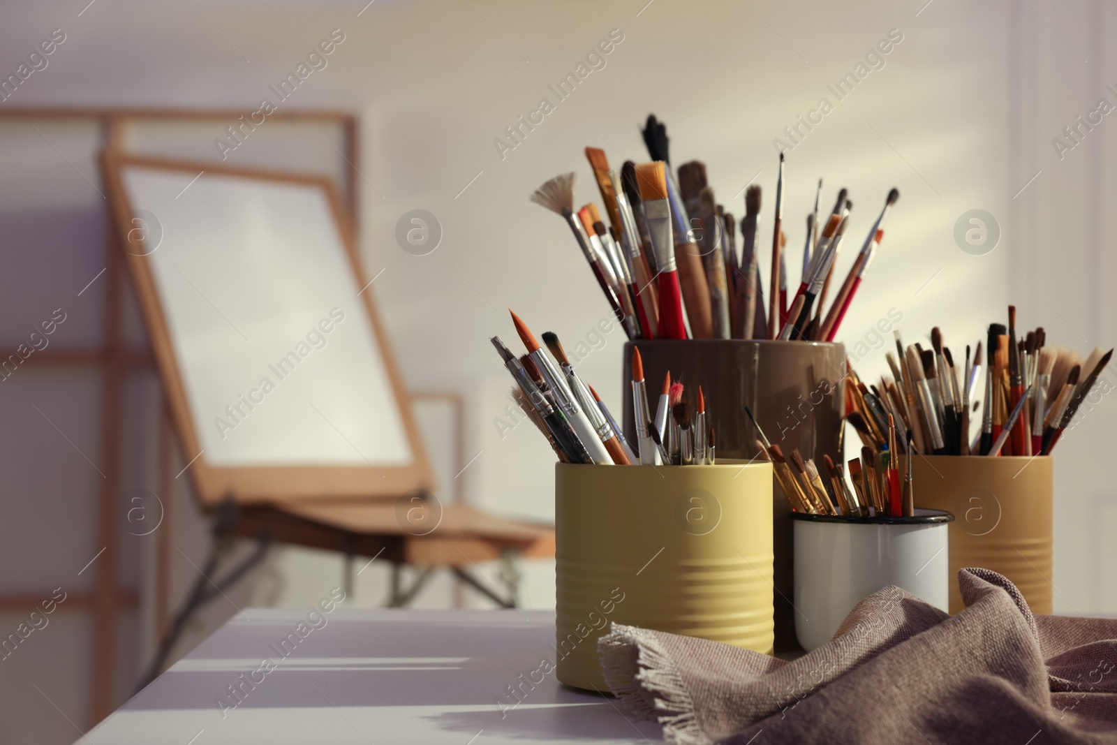 Photo of Different paintbrushes on white table in studio, space for text. Artist's workplace