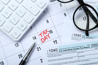 Calendar with date reminder about tax day, documents, glasses, pen and calculator, top view