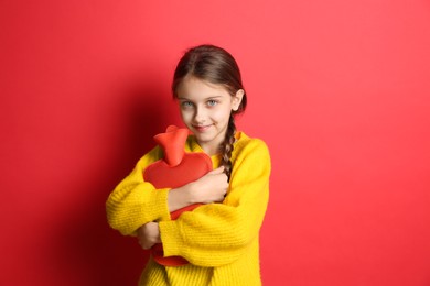 Photo of Ill girl with hot water bottle suffering from cold on red background