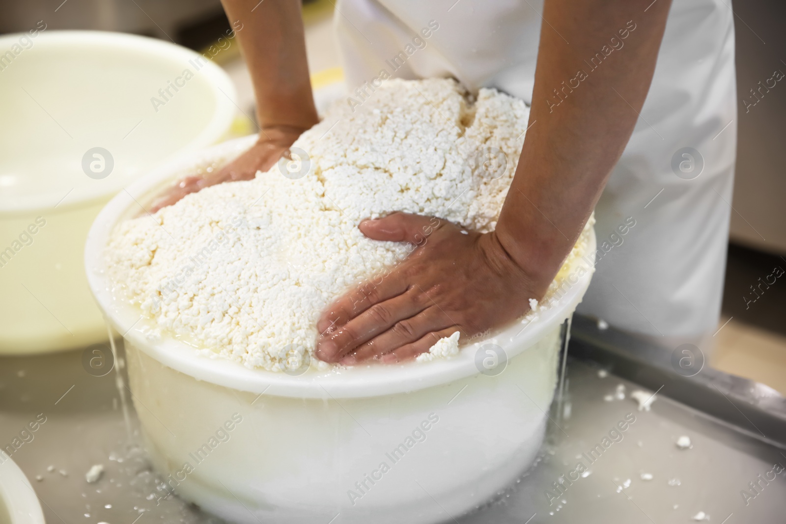 Photo of Worker pressing curd into mould at cheese factory, closeup