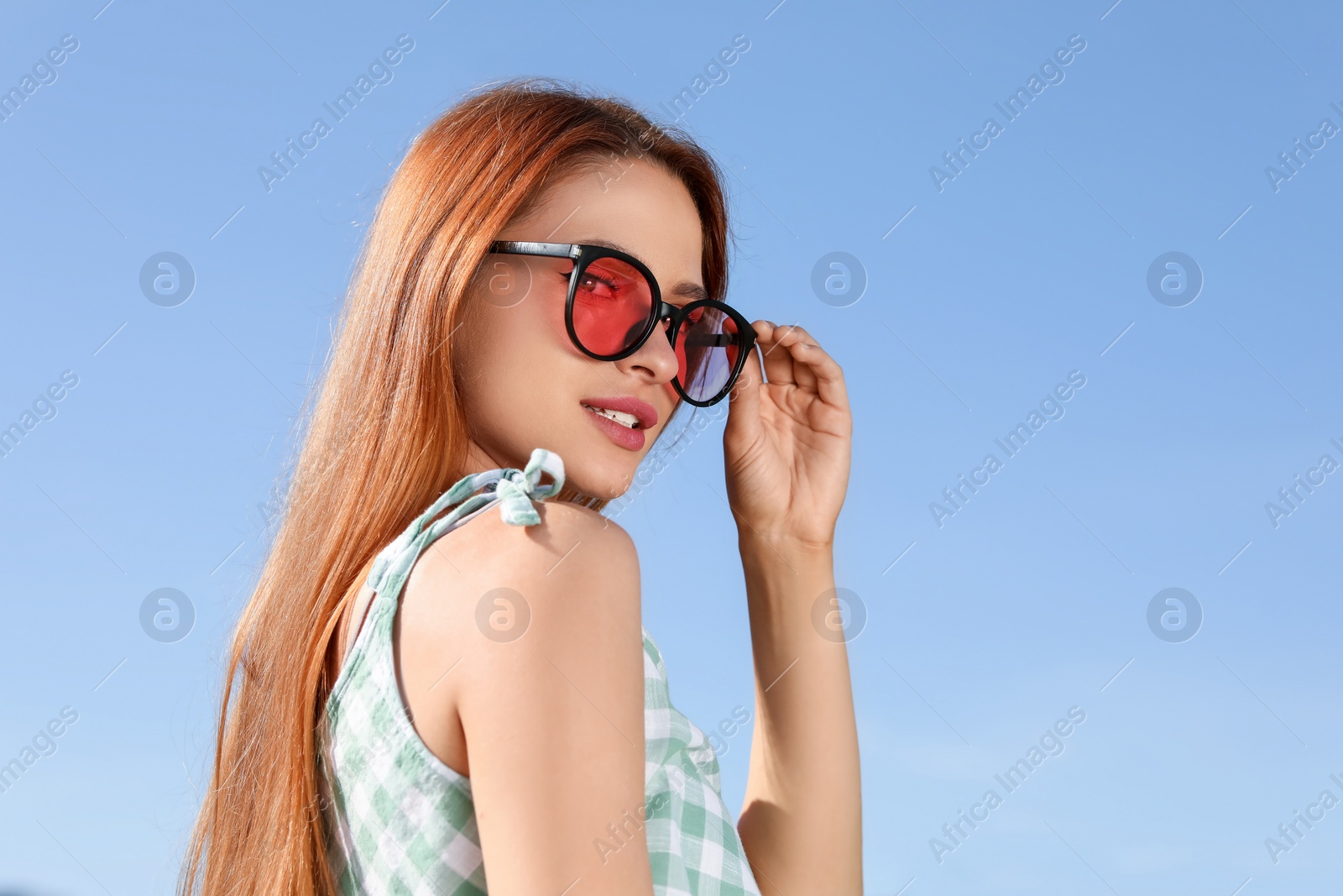 Photo of Beautiful woman in sunglasses against blue sky, space for text