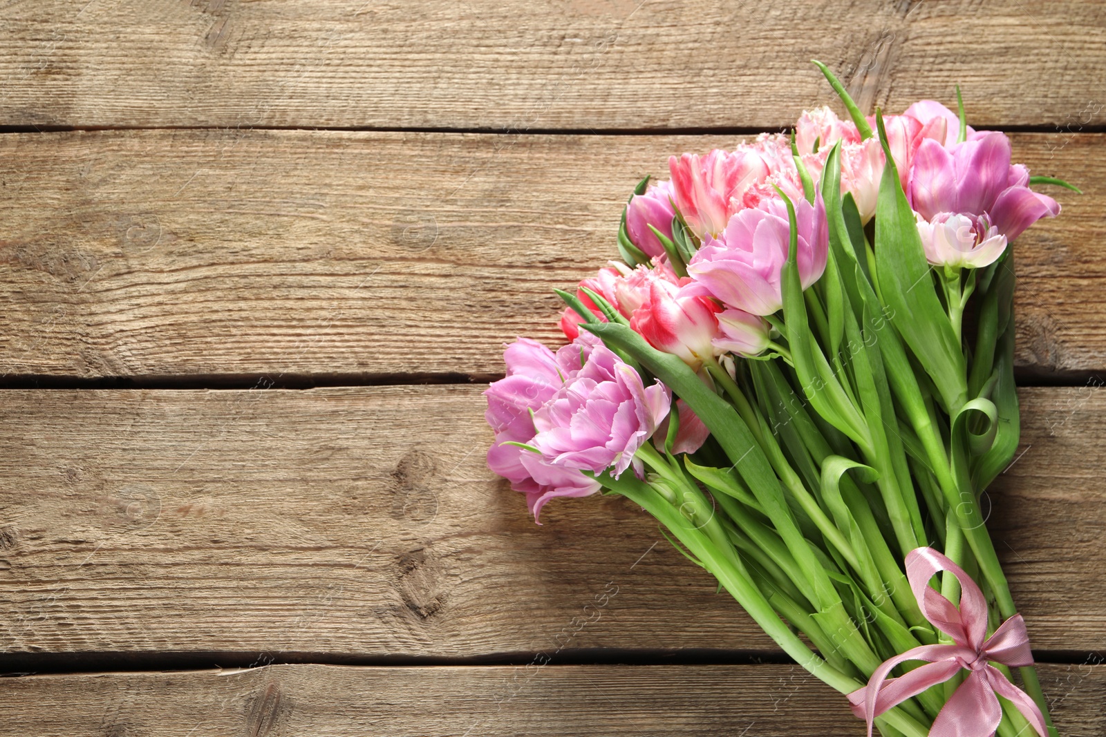 Photo of Beautiful bouquet of colorful tulip flowers on wooden table, top view. Space for text