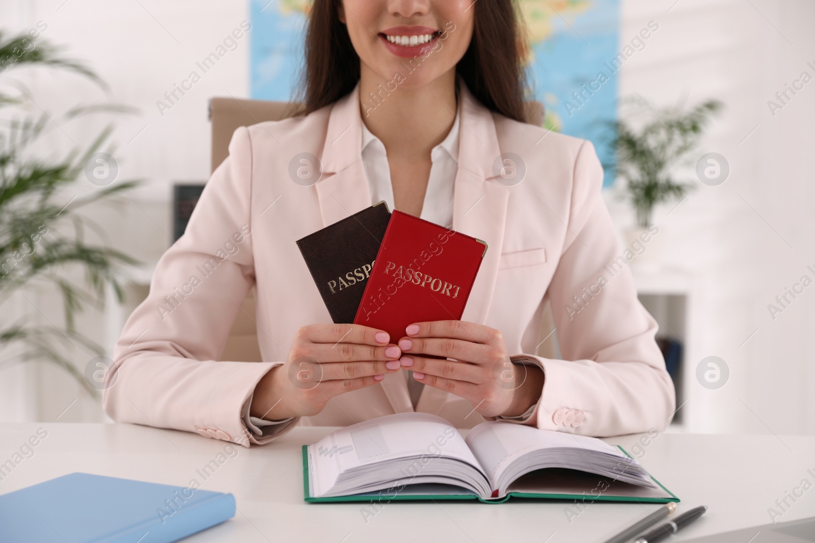 Photo of Happy manager holding passports at desk in travel agency, closeup