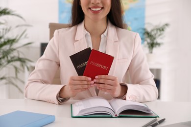 Happy manager holding passports at desk in travel agency, closeup