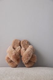 Photo of Soft beige slippers near grey wall, space for text