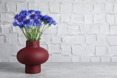 Photo of Bouquet of beautiful cornflowers in vase on light table. Space for text