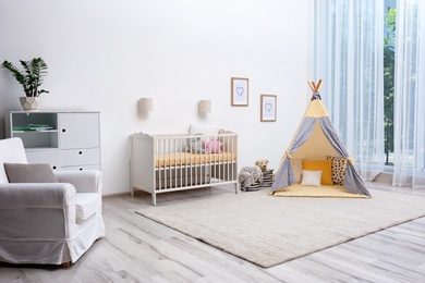 Photo of Cozy baby room interior with play tent and toys