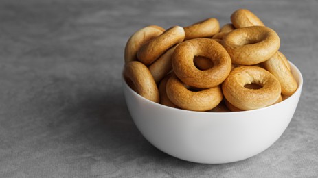 Photo of Bowl of tasty dry bagels (sushki) on grey table, closeup. Space for text