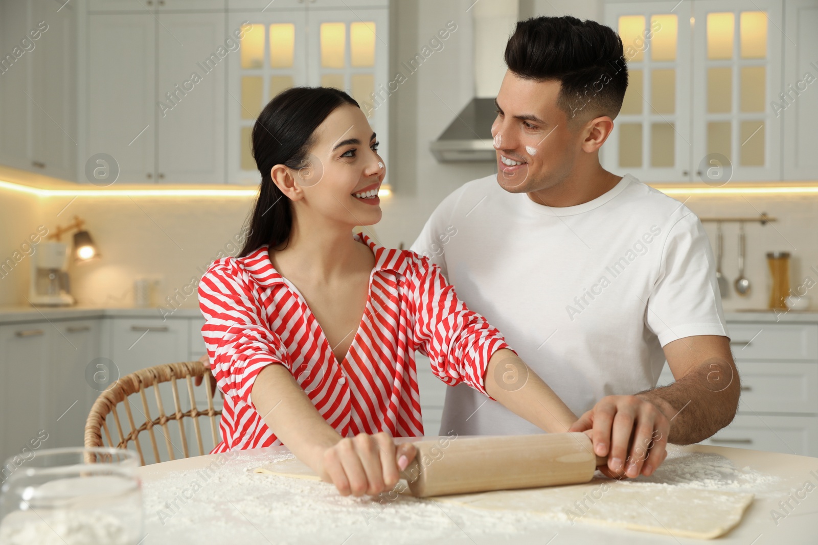 Photo of Happy couple wearing pyjamas and cooking together in kitchen