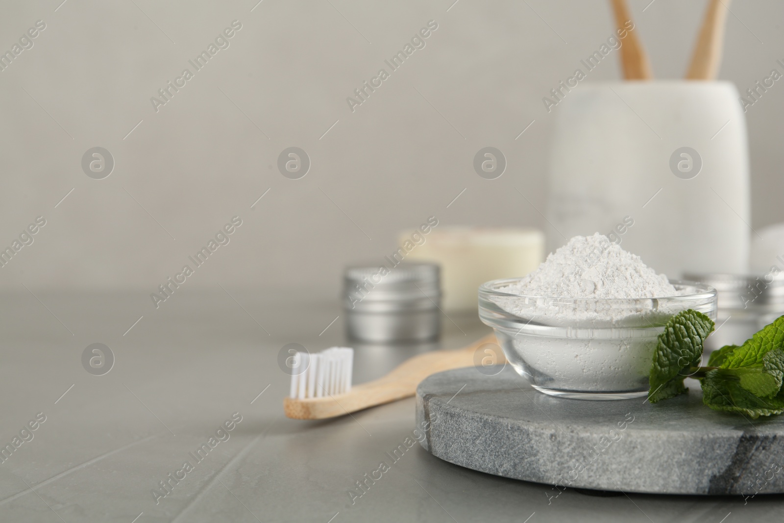 Photo of Tooth powder, brush and mint on grey table, closeup. Space for text