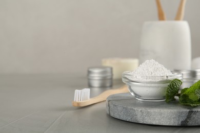 Tooth powder, brush and mint on grey table, closeup. Space for text