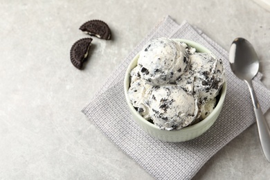 Photo of Bowl with ice cream and crumbled chocolate cookies on grey background, space for text