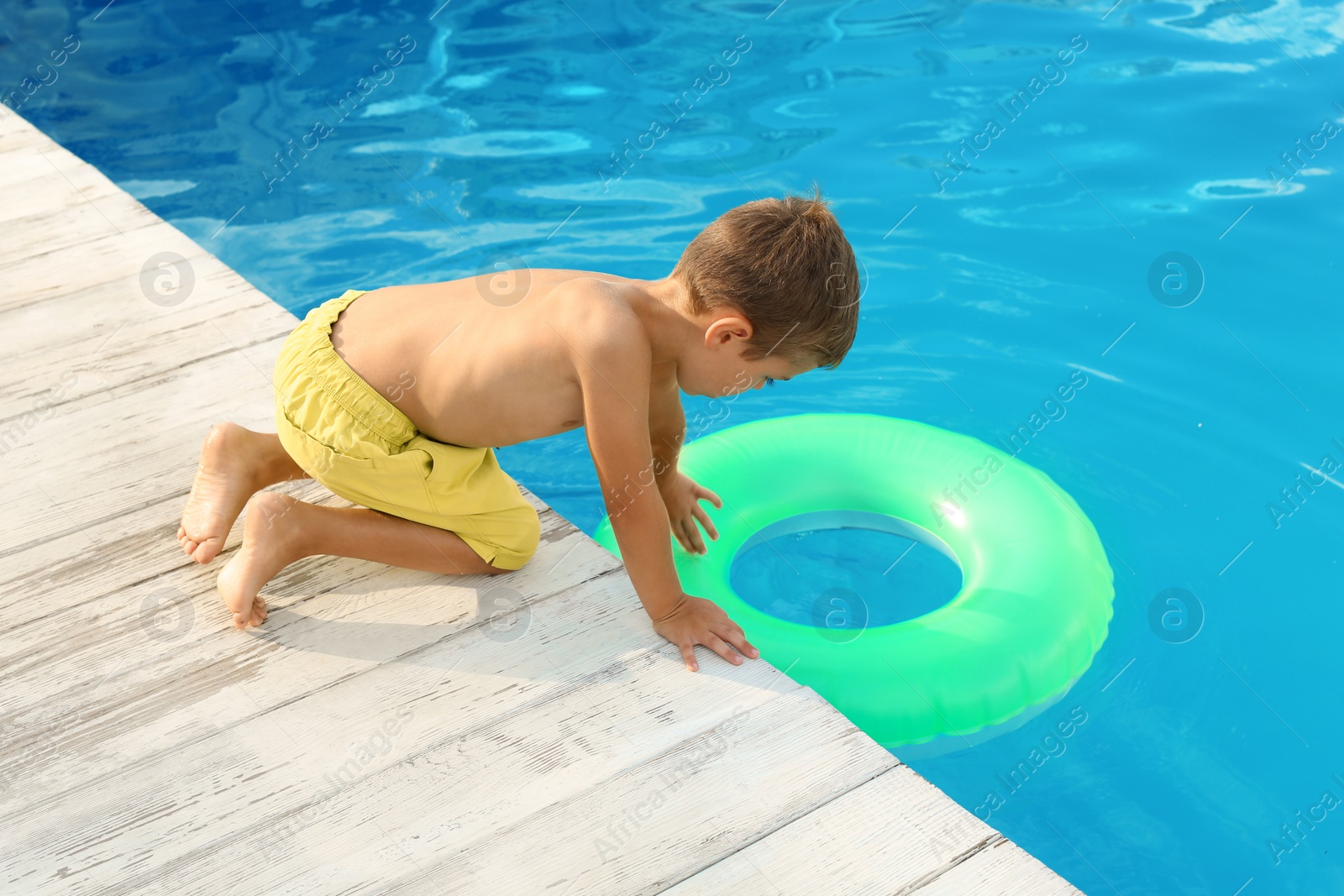 Photo of Little child reaching for inflatable ring in outdoor swimming pool. Dangerous situation